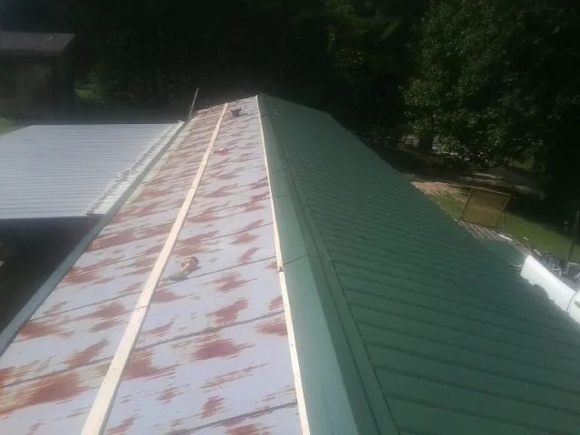 Old rusted panels beside newly installed green metal roofing — Wind Damage Roof Repair by Roofing Brothers in Issue