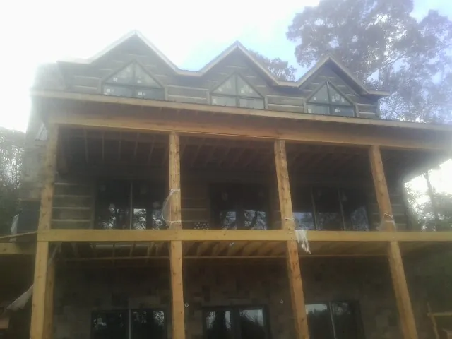 Dormers and porch framing on a large log home under construction — Roof Coating work by our crew in Issue