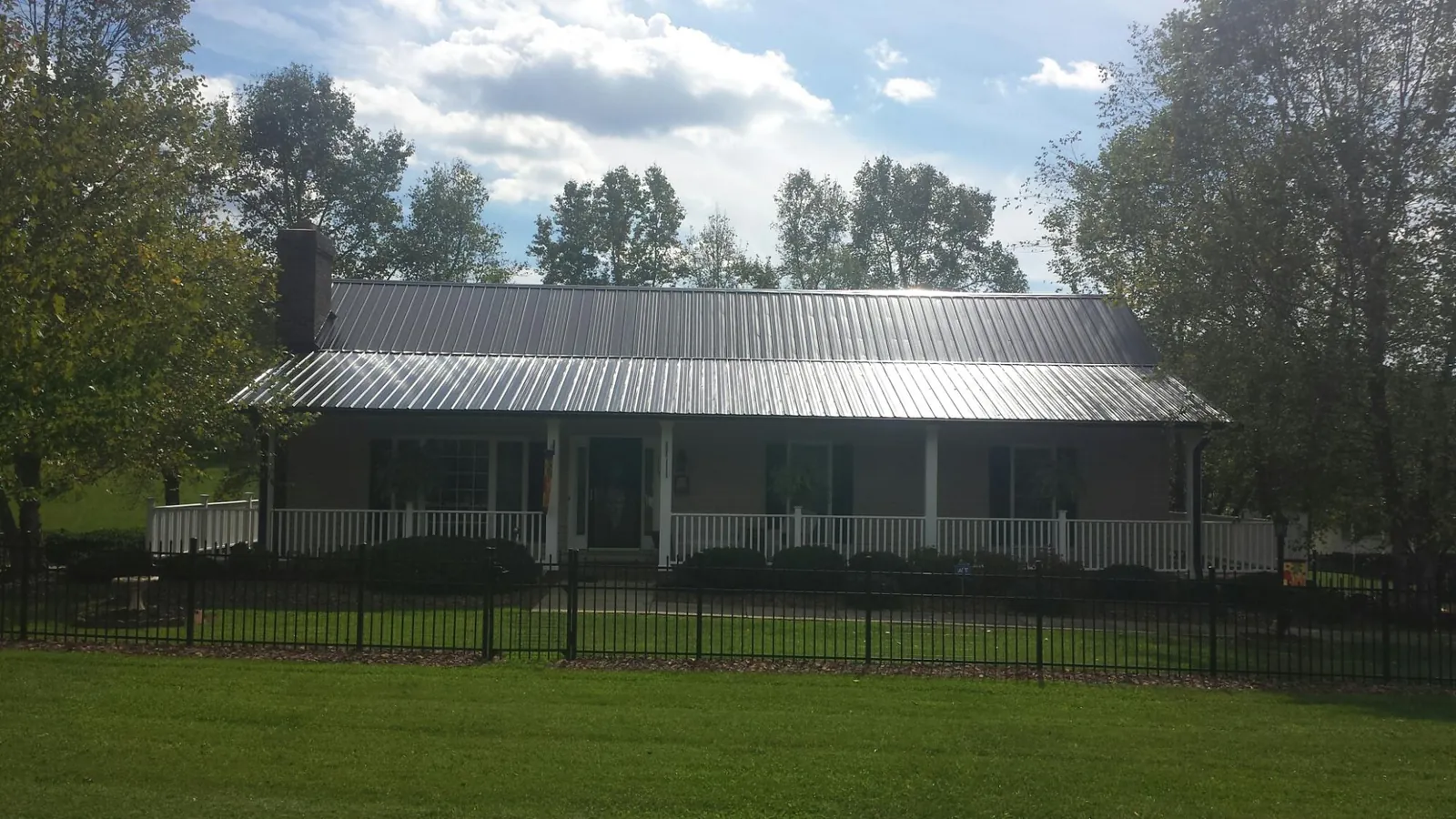 Gray metal roof on a brick ranch with a full width front porch — Gutter Guard Installation work by our crew in Issue