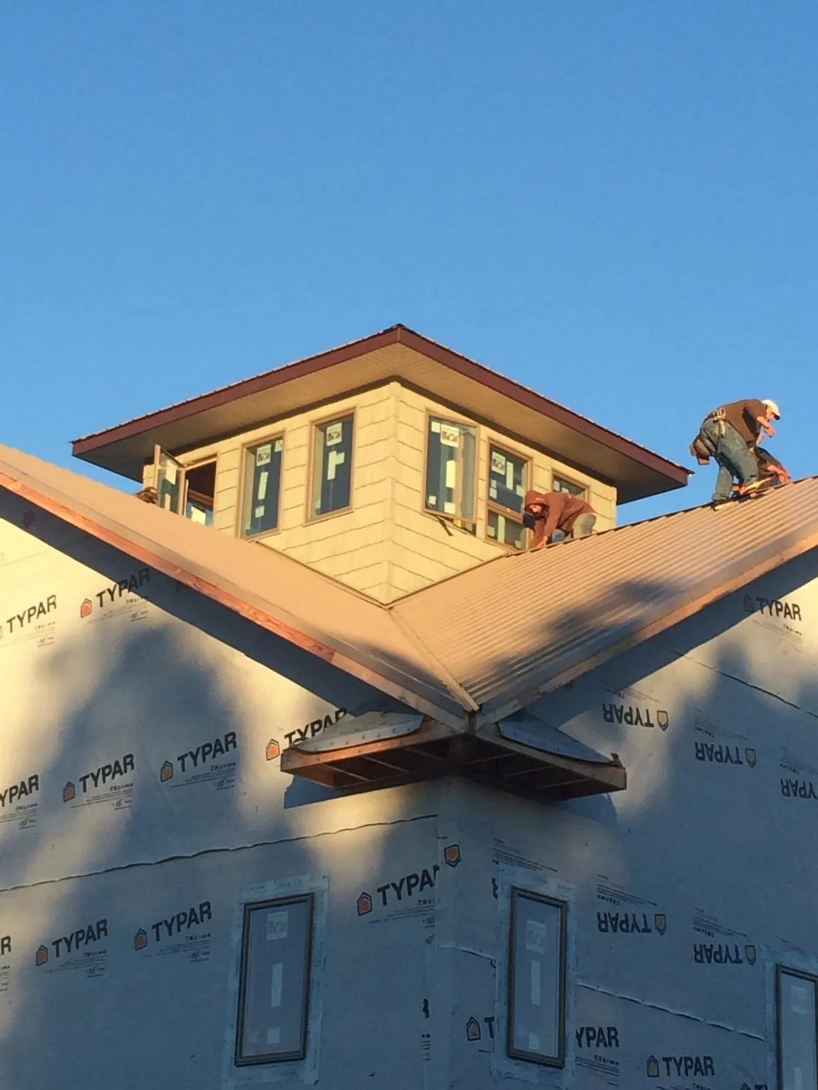 Roofers working around a rooftop cupola on a new metal roof at sunset — Roof Waterproofing in Issue by Roofing Brothers